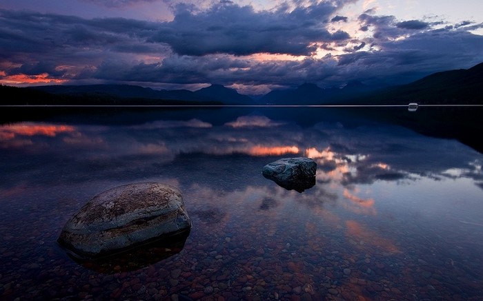 Sunset over a calm lake with mountains and rocks