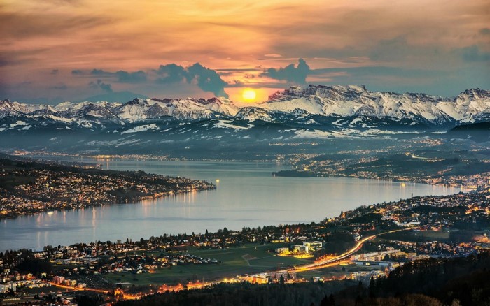 Zurich cityscape and snowy mountains at sunset