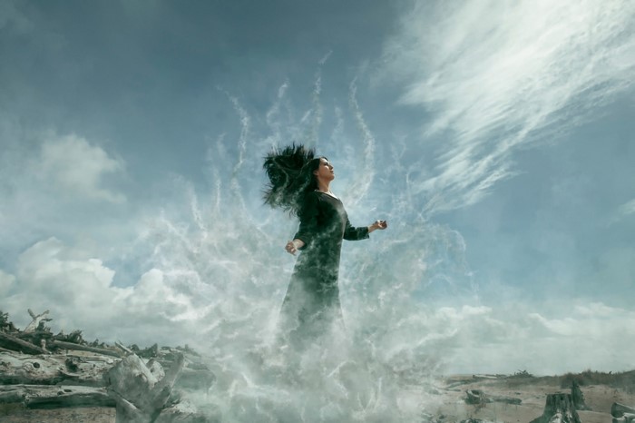 Woman dissolving into smoke against a cloudy sky