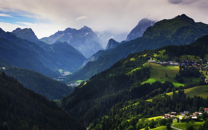Mountain valley village with lush green hills and dramatic peaks
