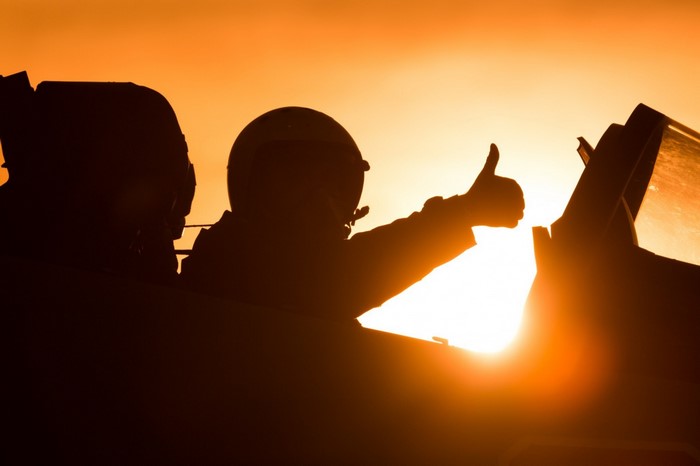 Pilot giving thumbs up in cockpit at sunset
