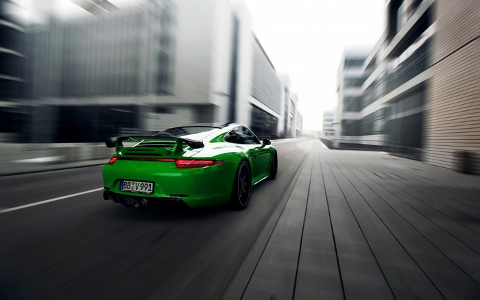 Green Porsche 911 Carrera 4S driving on a city street