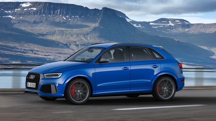 Blue Audi RS Q3 performance (8U) driving on a road with mountains
