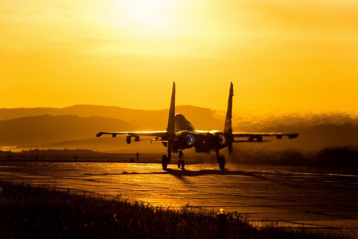 Sukhoi Su-27 fighter jet taking off at sunset