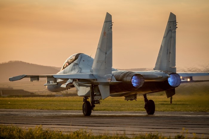 Sukhoi Su-35 fighter jet on runway with engines on