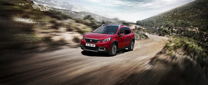 Red Peugeot 2008 driving on a dirt road