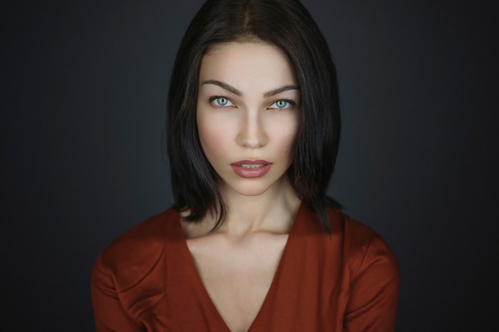 Woman with dark hair and blue eyes in a red top