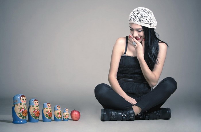 Woman in black outfit with Matryoshka dolls and apple