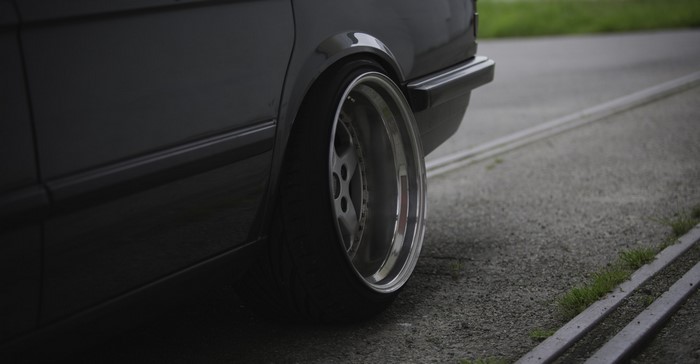 Close-up of a dark car's rear wheel and bumper