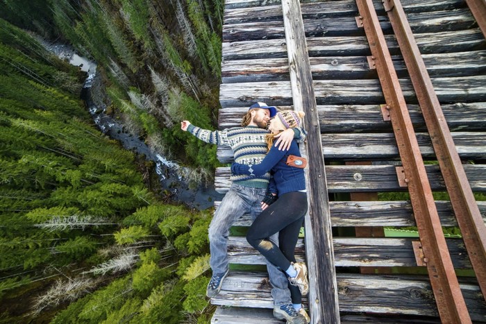 Couple lying on a wooden bridge over a forest