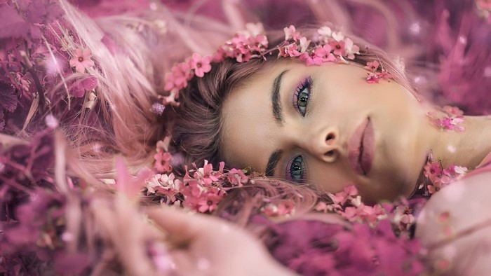 Woman Lying Among Pink Flowers with Soft Gaze