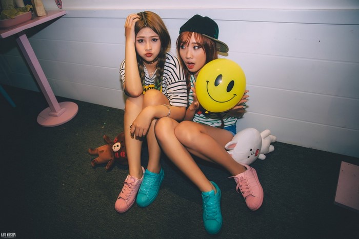 Two young Asian women sitting with toys and a balloon