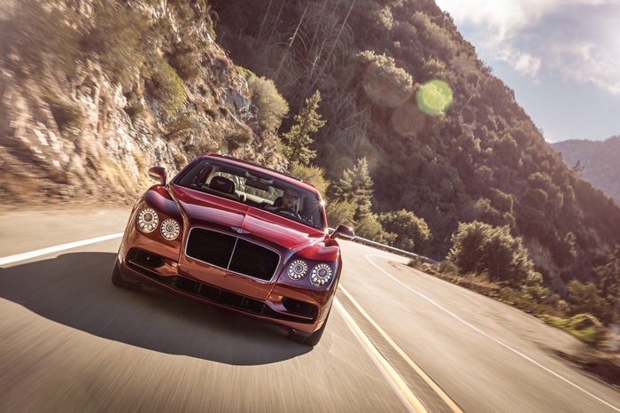 Red Bentley Flying Spur V8 S driving on a mountain road