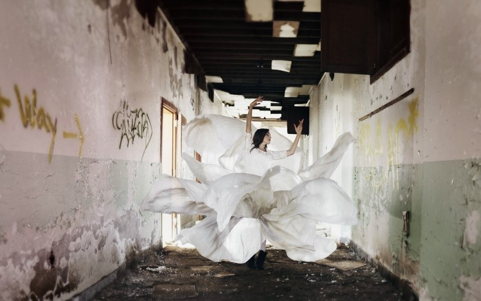 Woman in white dress dancing in abandoned hallway
