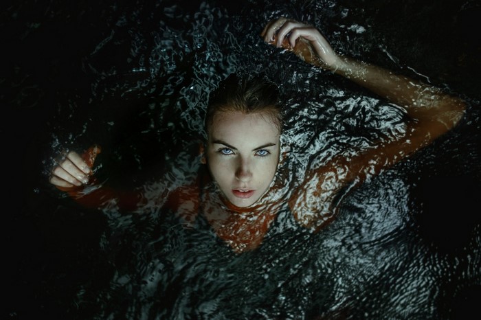Woman with blue eyes in dark water