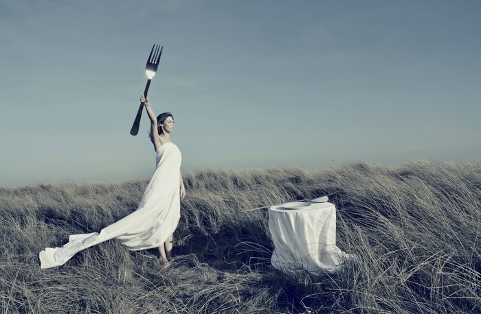Woman in white dress holding a giant fork outdoors