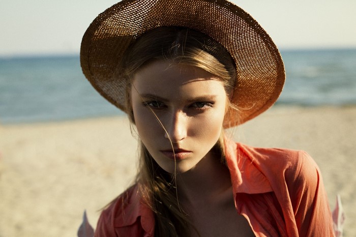 Woman wearing a straw hat and orange shirt on a beach