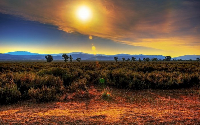 Sunset over a vast field with mountains in the distance