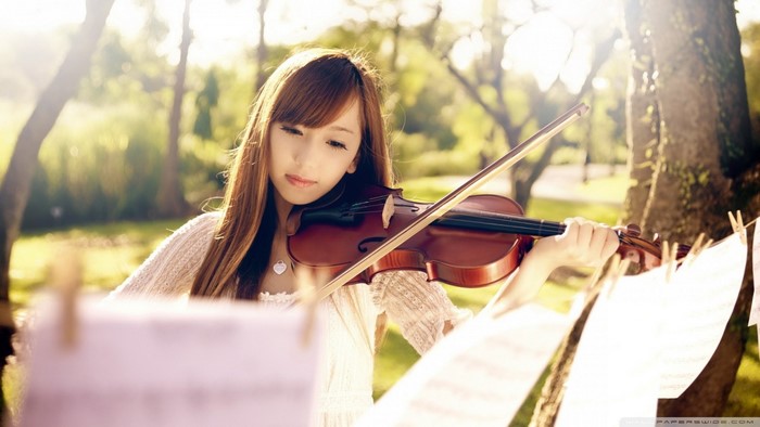 Asian girl playing violin outdoors