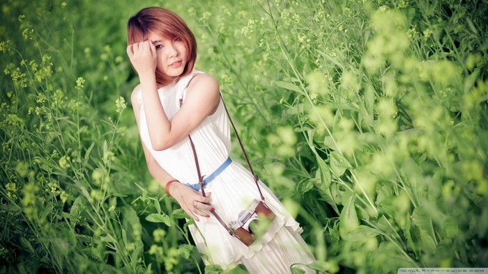 Asian woman in white dress with camera in green field