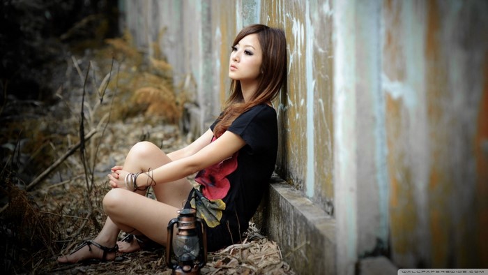 Woman sitting by a wall with a lantern