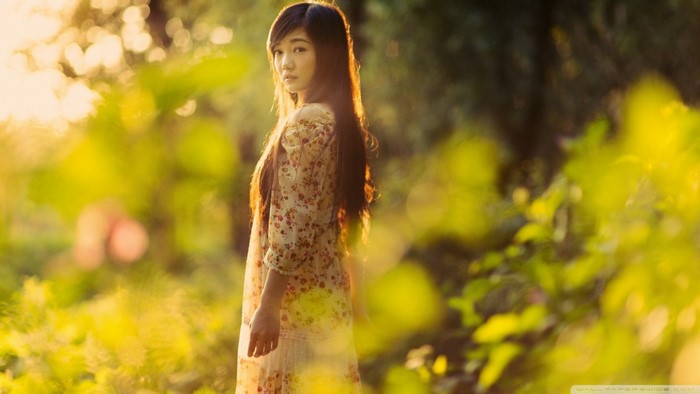 Asian woman with long hair in a floral dress in sunlight