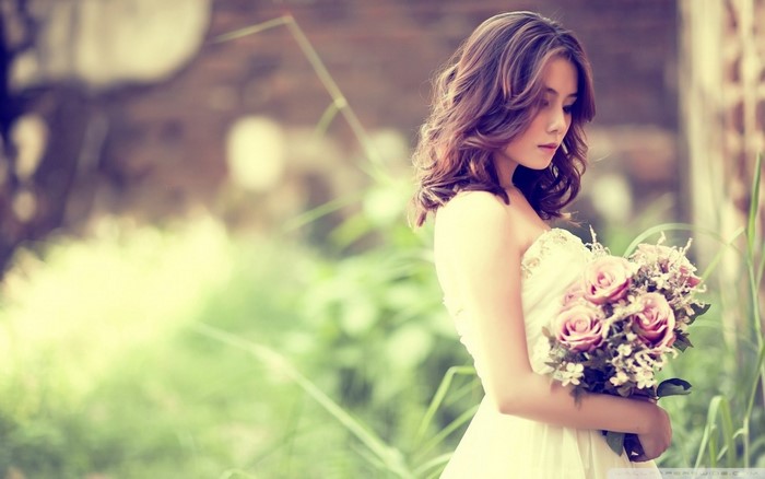 Woman in white dress holding a bouquet of roses