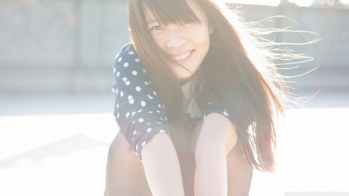 Young woman with long brown hair smiling outdoors