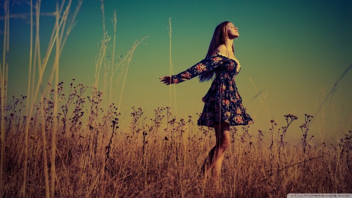 Woman in floral dress in a field at sunset