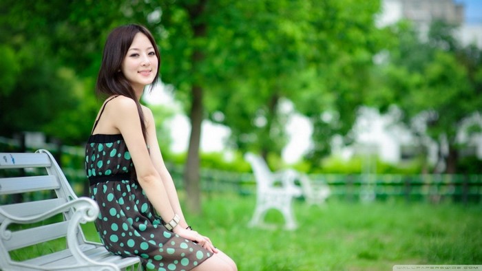 Asian Woman Sitting on Park Bench in Polka Dot Dress