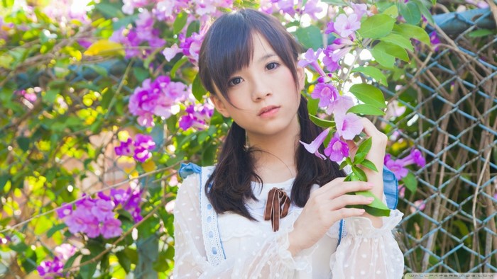 Young Asian woman with pigtails in a white dress among purple flowers
