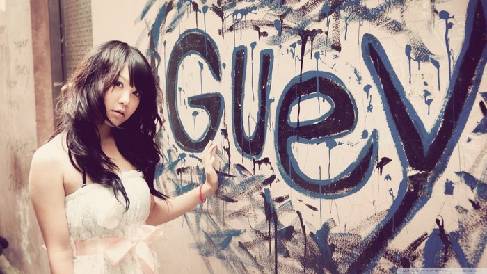 Asian woman in white dress near graffiti wall