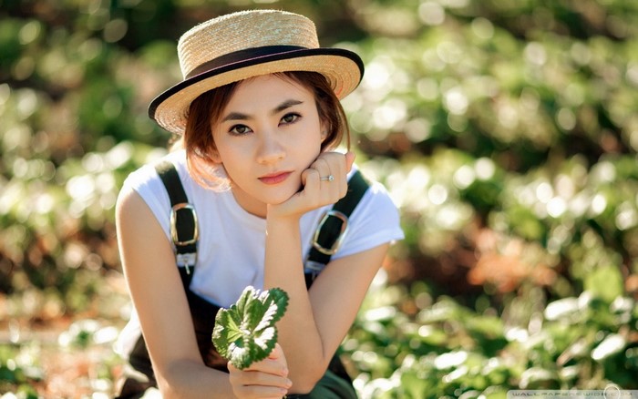 Woman wearing a straw hat and overalls in a field