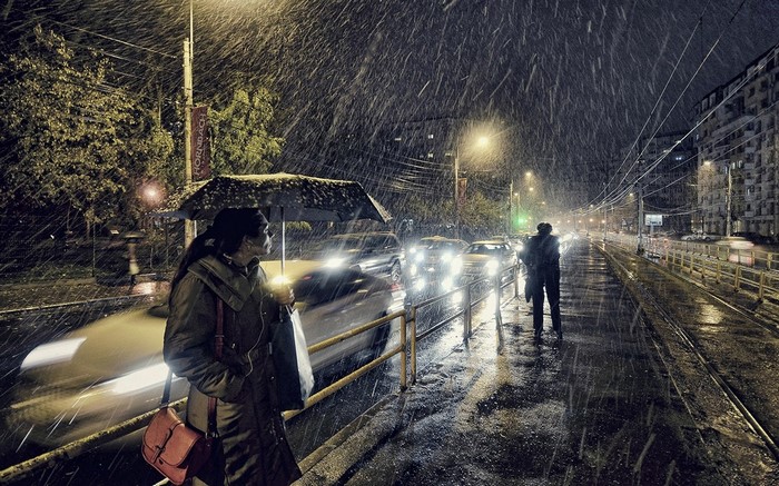 People with umbrellas in the snow at night