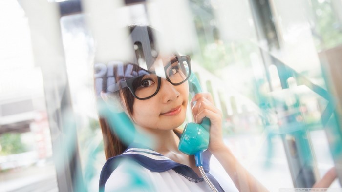Asian woman wearing glasses and school uniform holding a phone