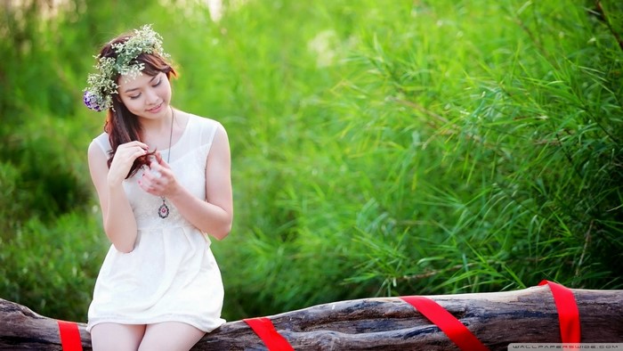 Young Woman in White Dress Sitting on Log Outdoors
