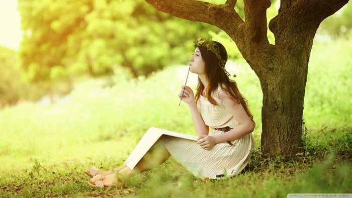 Woman with flower crown sitting under a tree