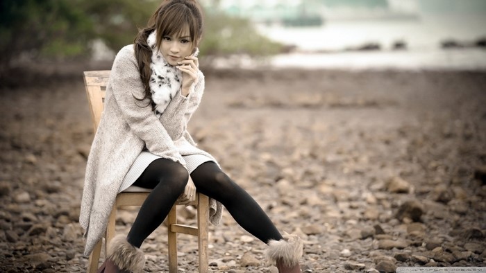 Asian woman sitting on a chair on a rocky shore
