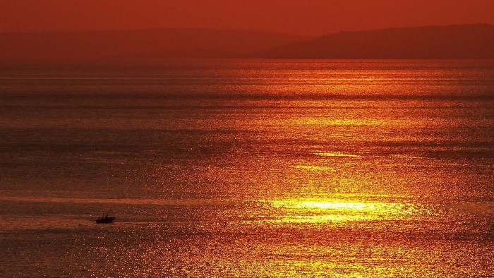 Boat on the sea during sunset with orange sky