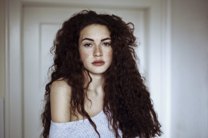 Woman with long wavy brown hair and freckles