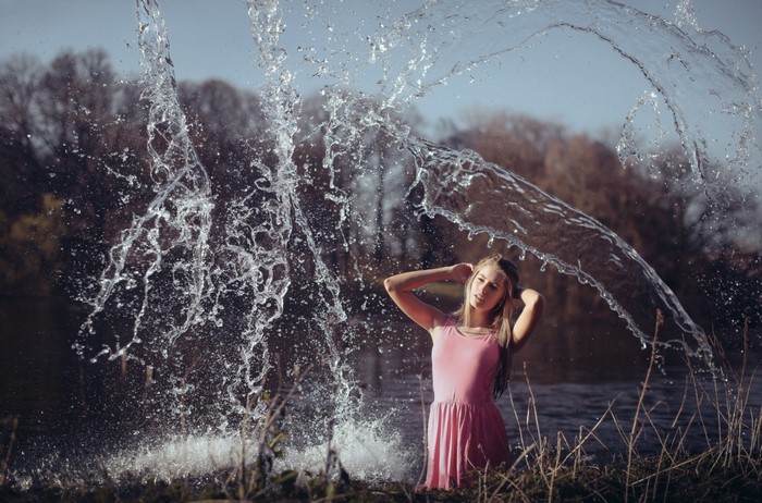 Girl in pink dress splashing in water