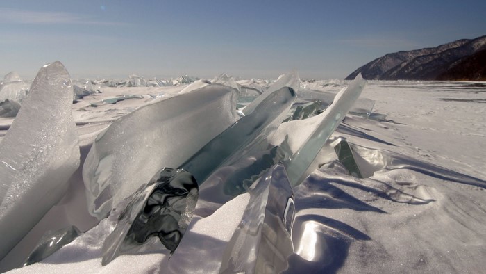 Broken ice formations on a snowy landscape with mountains