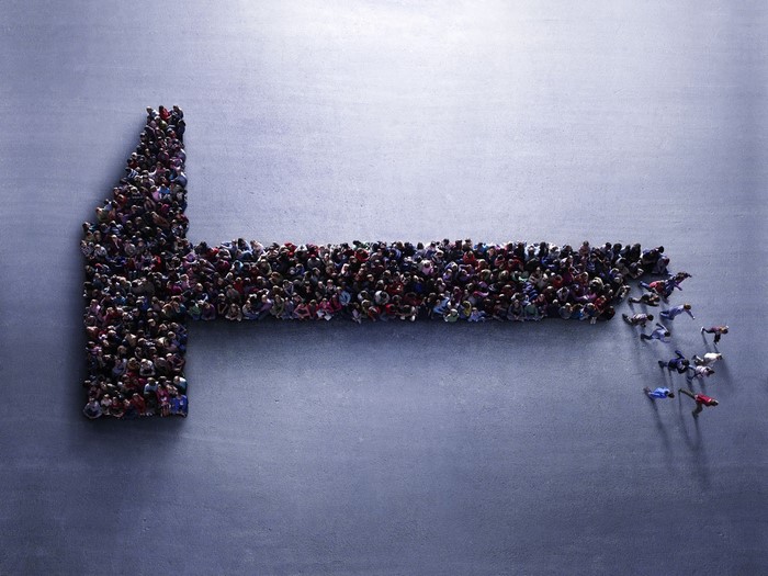 People forming an arrow shape on a blue surface