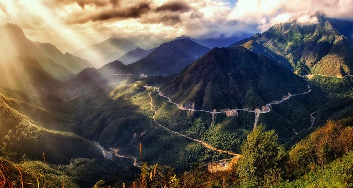 Sun rays over a winding road in a mountain valley