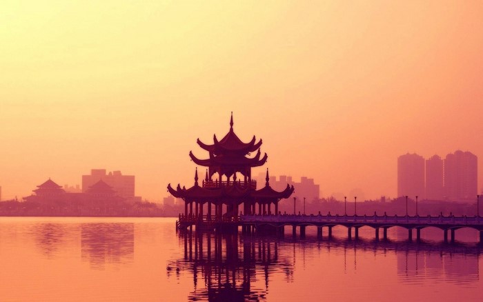 Pagoda on a lake at sunset with city skyline