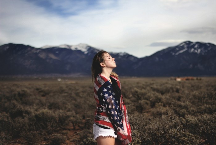 Woman wrapped in American flag in front of mountains
