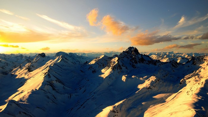 Snow-covered mountains at sunset with dramatic clouds