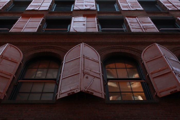 Building facade with red shutters and arched windows