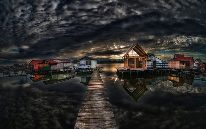 Floating houses on a lake at dusk with dark clouds