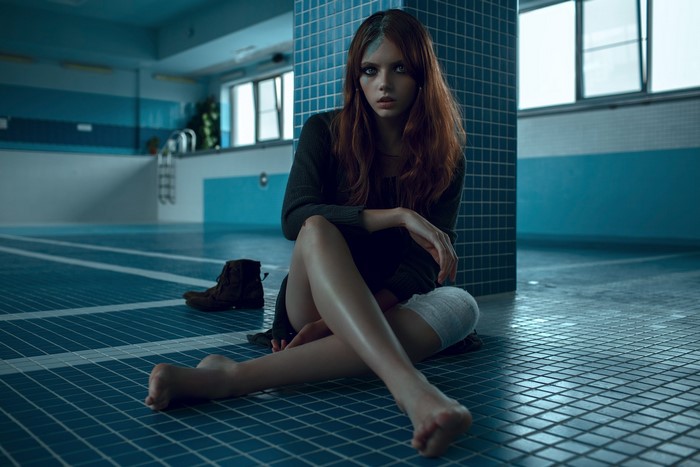 Woman sitting by a tiled swimming pool